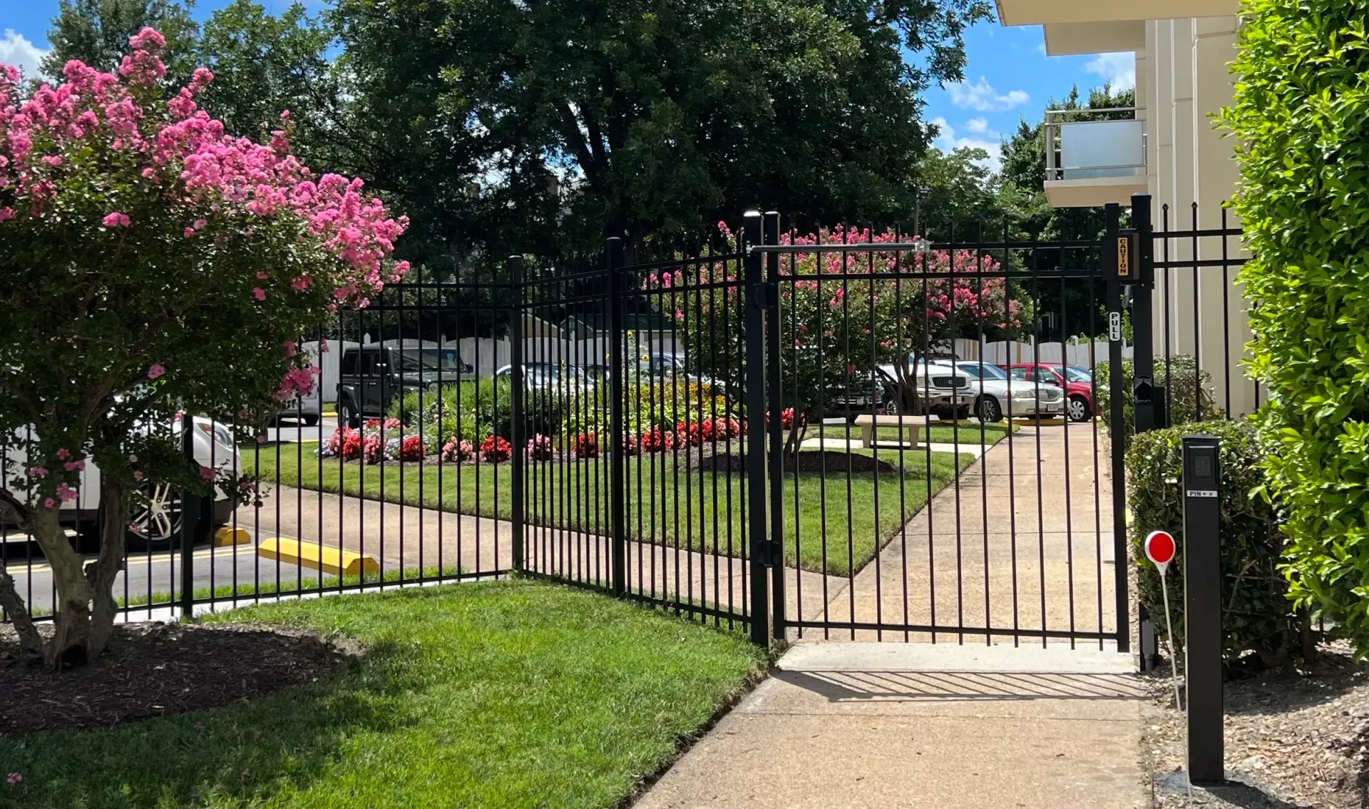 A black metal fence surrounds a walkway leading to a building.