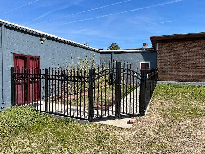A black fence with a gate in front of a brick building.