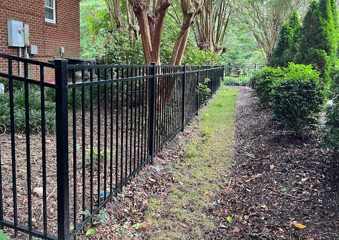 A black metal fence surrounds a lush green yard.