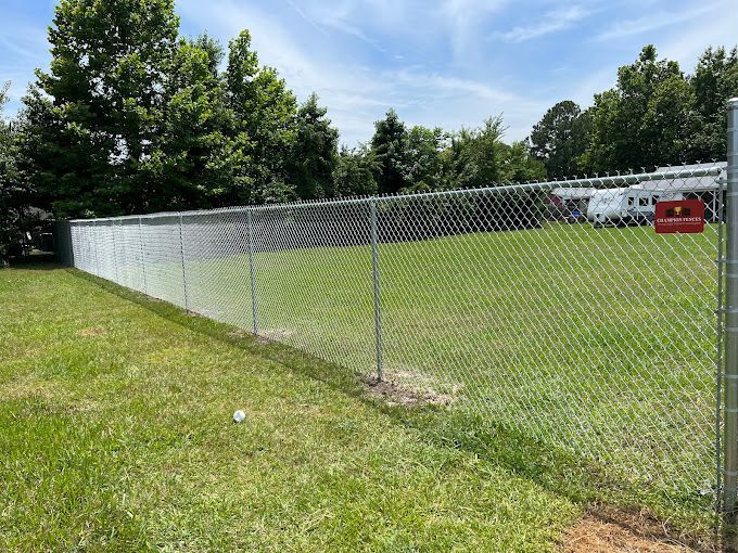 A chain link fence surrounds a large grassy field.