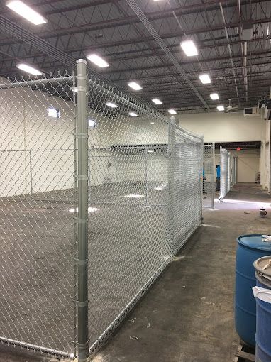 There is a chain link fence in the middle of a warehouse.