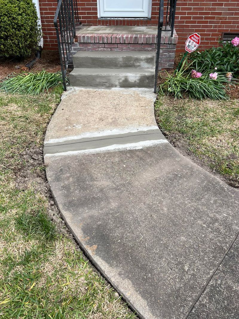 A concrete walkway leading to the front door of a house.