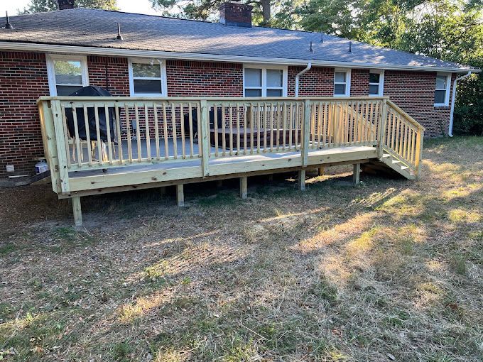 A wooden deck is sitting in front of a brick house.