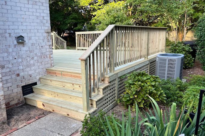 A wooden deck with stairs and a brick building in the background.