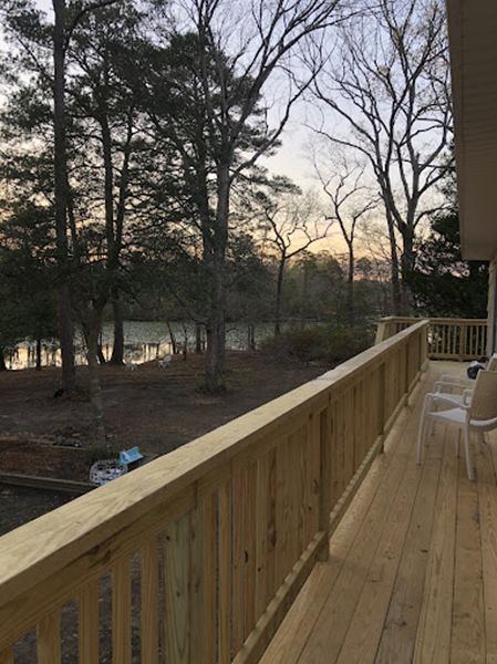 A wooden deck with a view of trees and a body of water