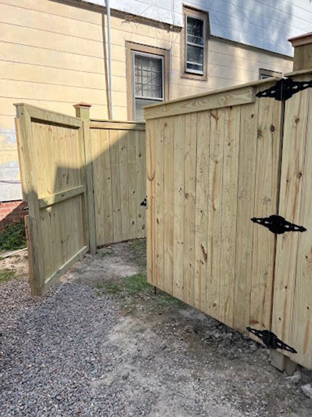 A wooden fence with a gate in front of a house.