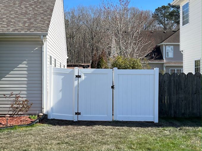 A white fence is in the backyard of a house.