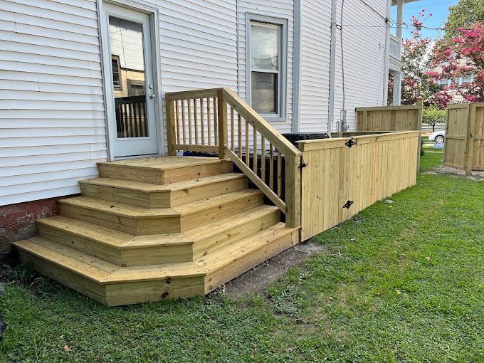 A wooden deck with stairs and a fence in front of a white house.