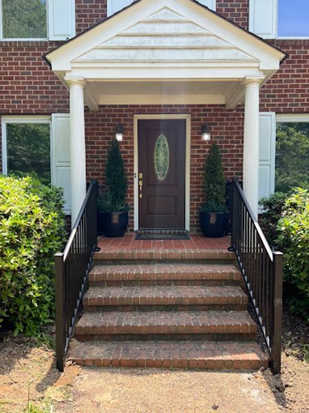 A brick house with a porch and stairs leading to the front door.