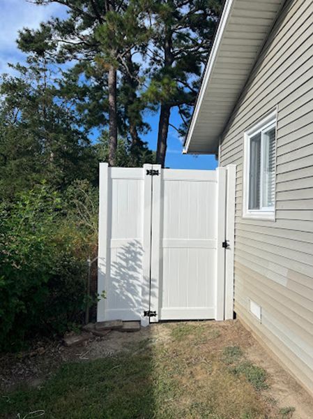 A white fence is attached to the side of a house.