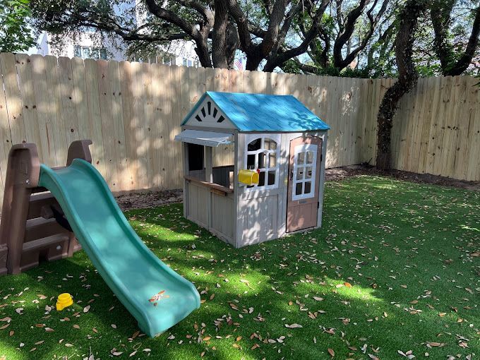 A playhouse with a slide and stairs in a backyard.