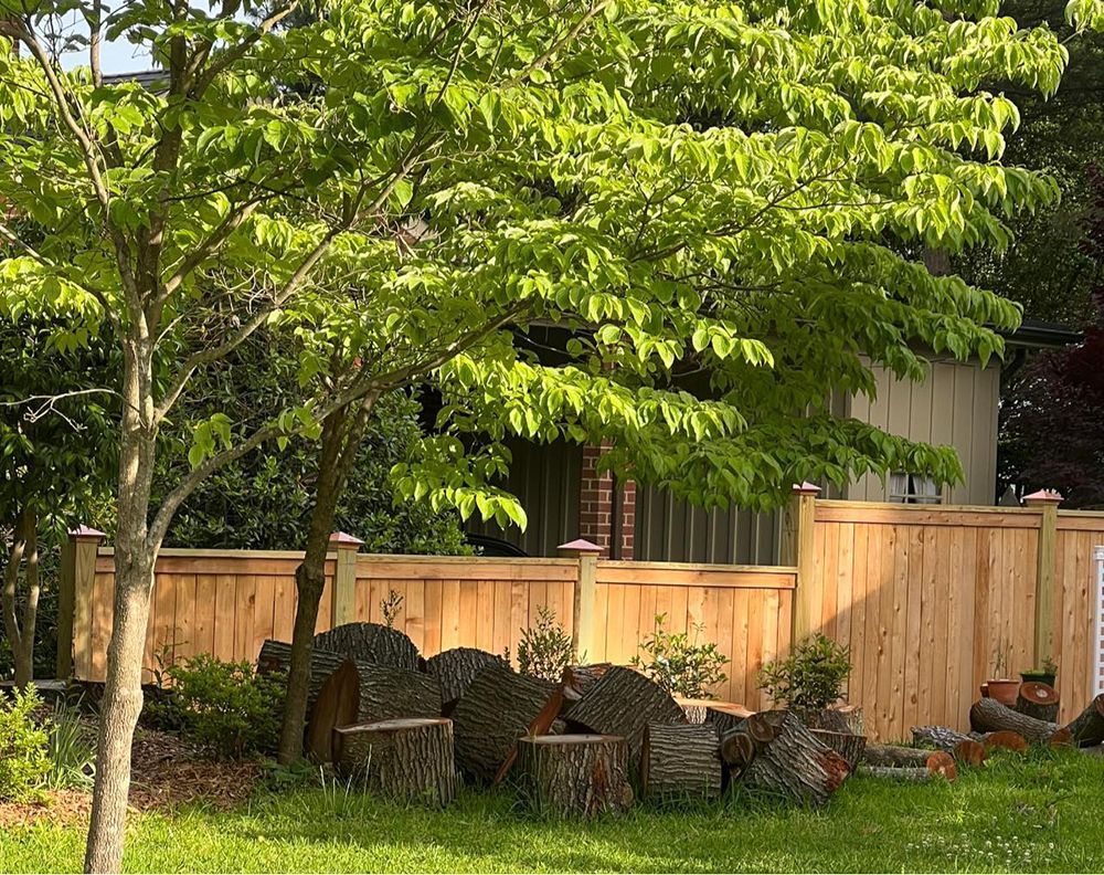 A wooden fence with a pile of logs in front of it