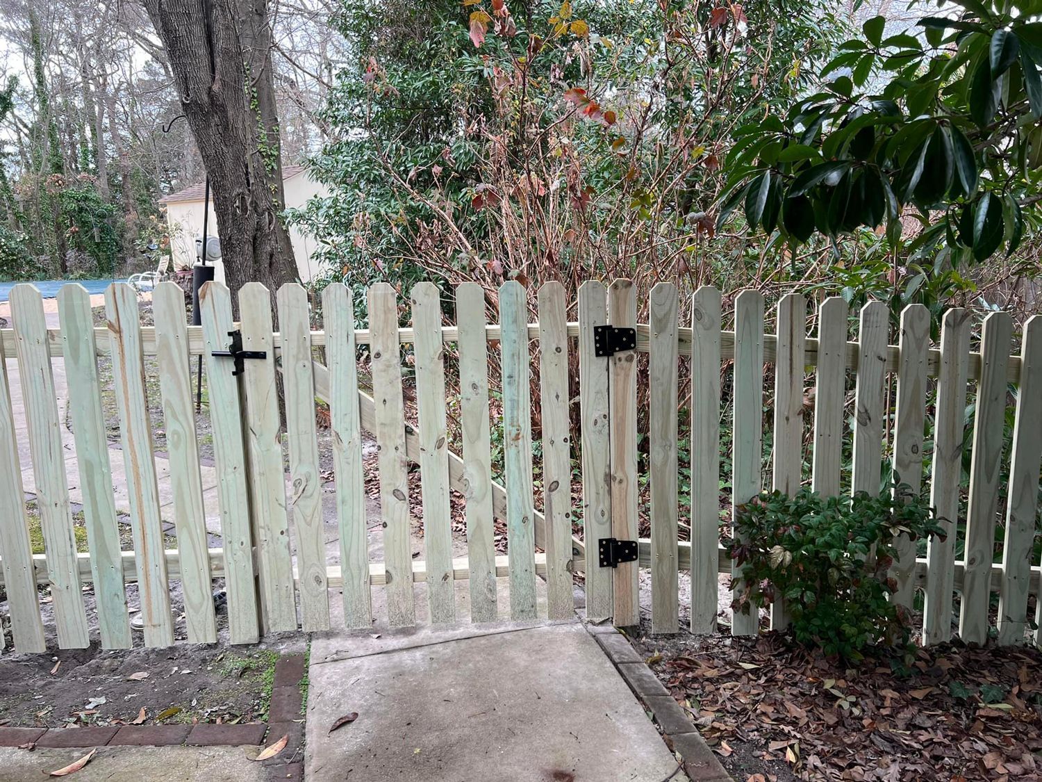 A wooden picket fence with a gate in the backyard.