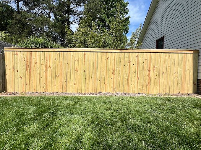 A wooden fence is sitting on top of a lush green lawn in front of a house.