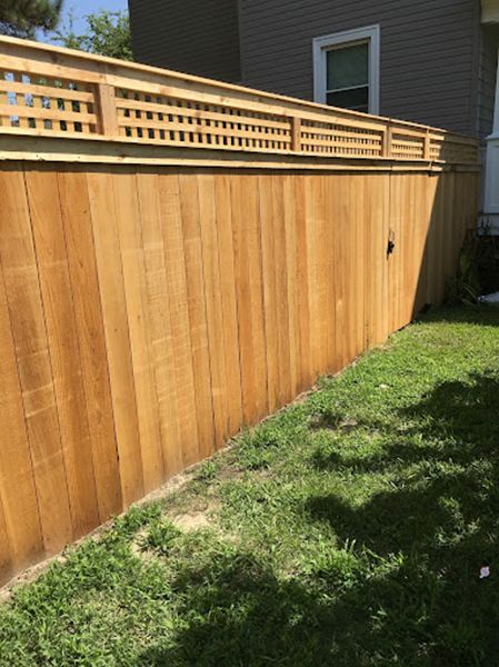A wooden fence is in the backyard of a house.