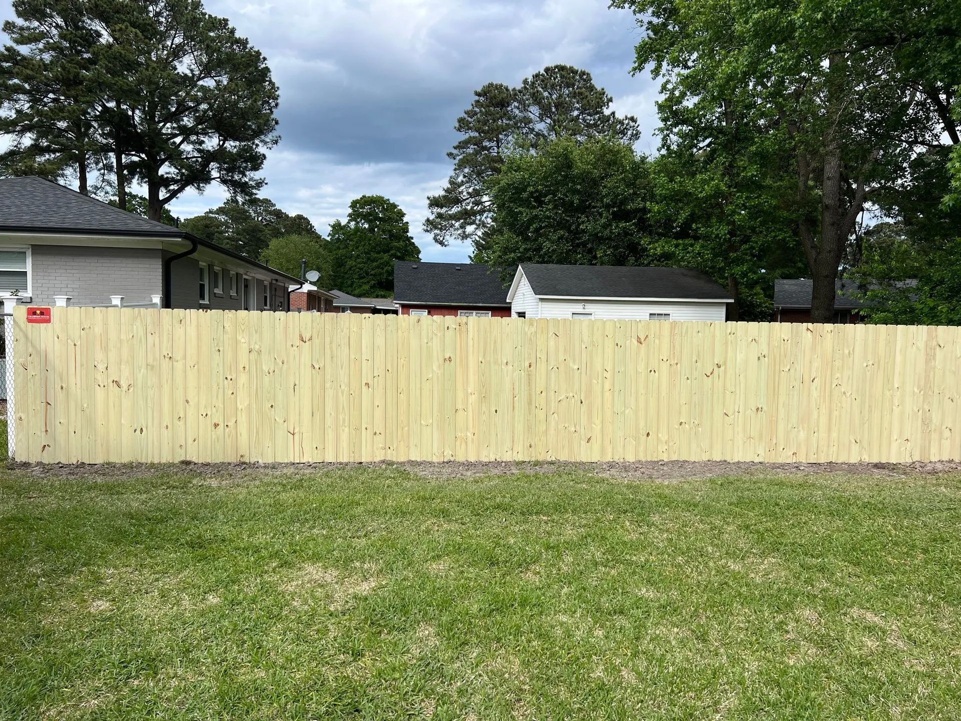 A wooden fence is in the backyard of a house.