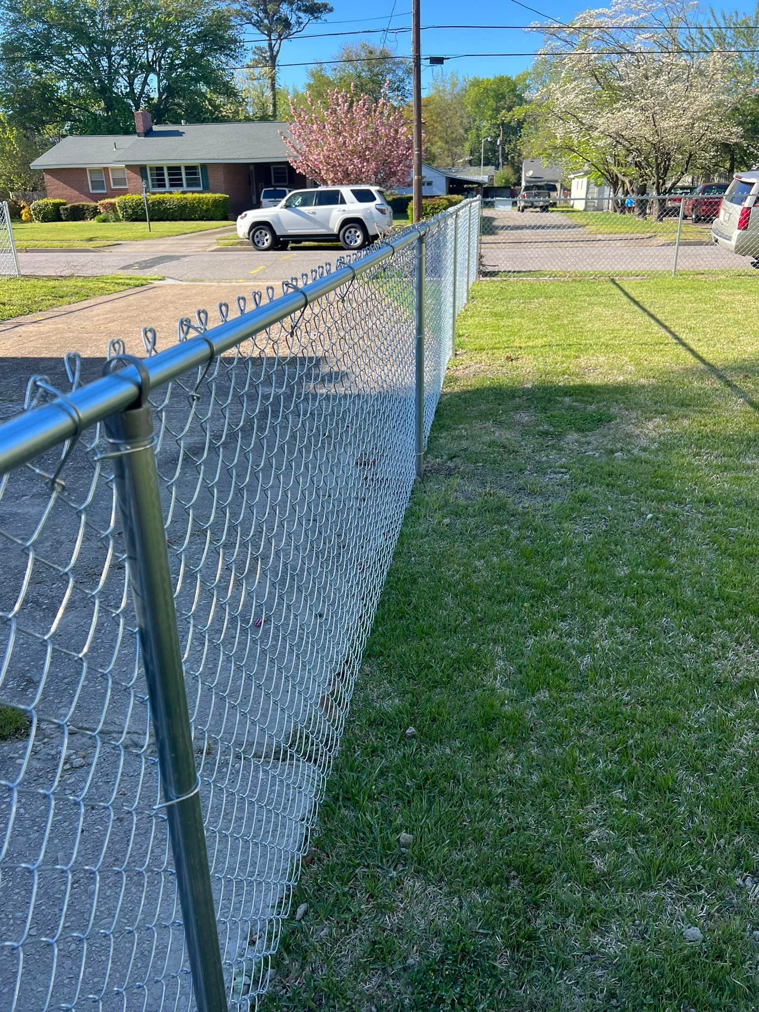A chain link fence is surrounding a lush green yard.