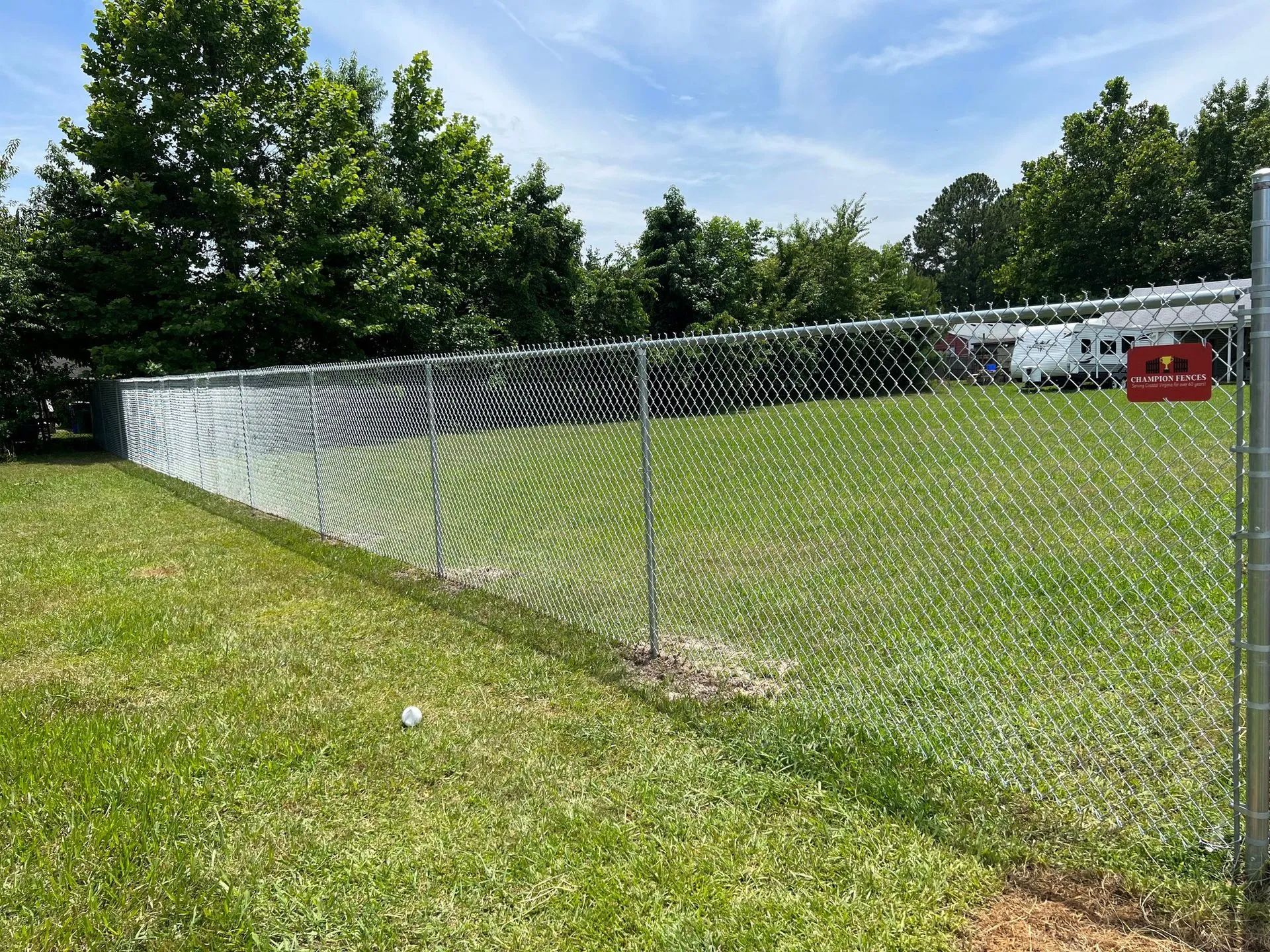 A chain link fence surrounds a large grassy field.