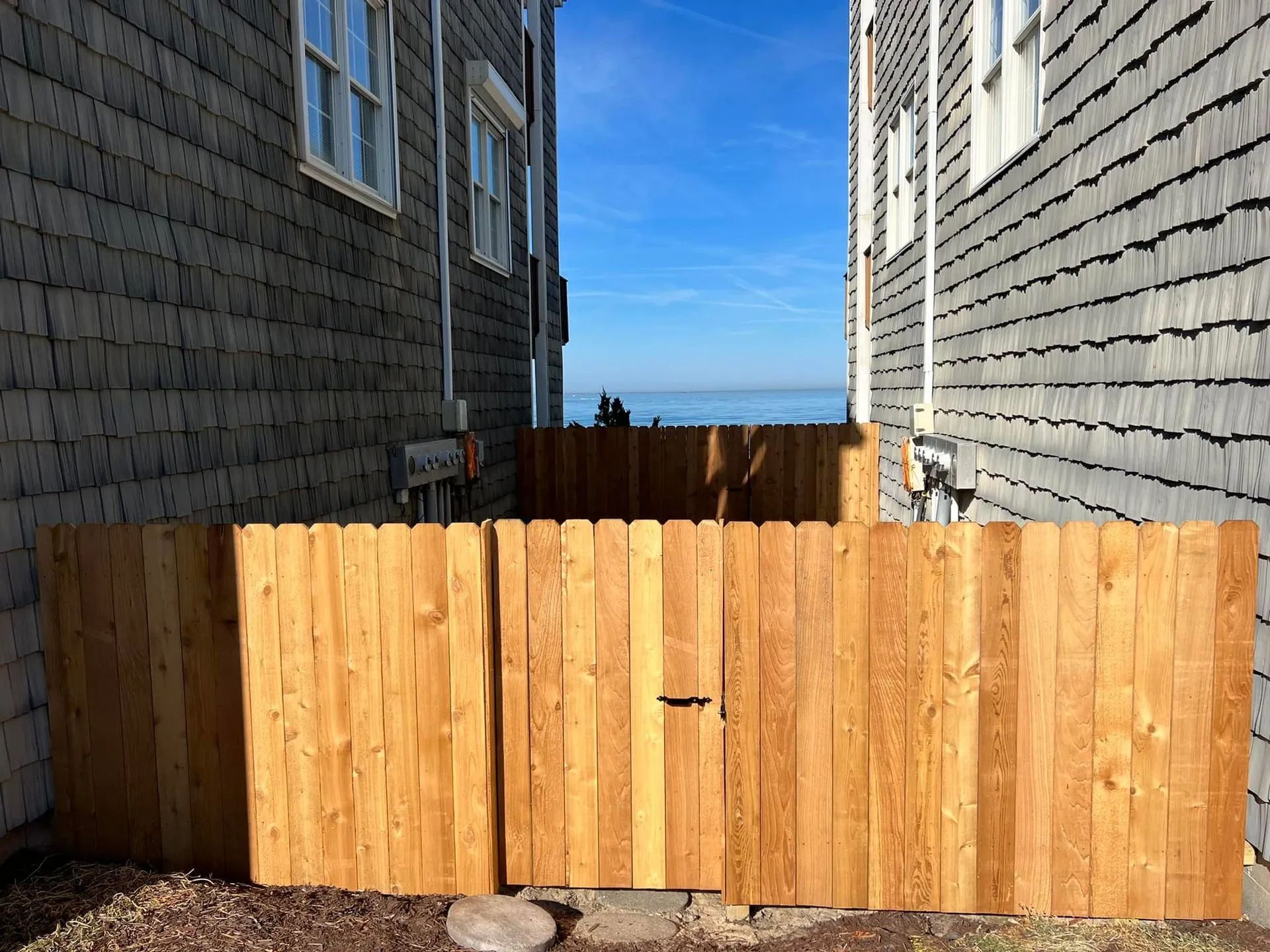 A wooden fence with a gate in front of a house.