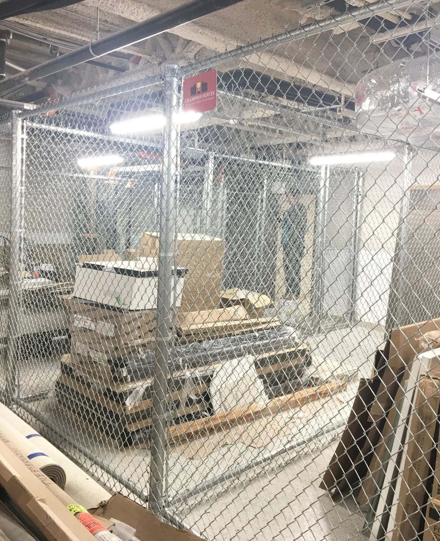 A room with a chain link fence and boxes on the floor.
