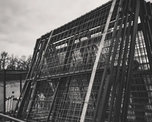 Metal cage-like structure against a blurred background of trees and sky.