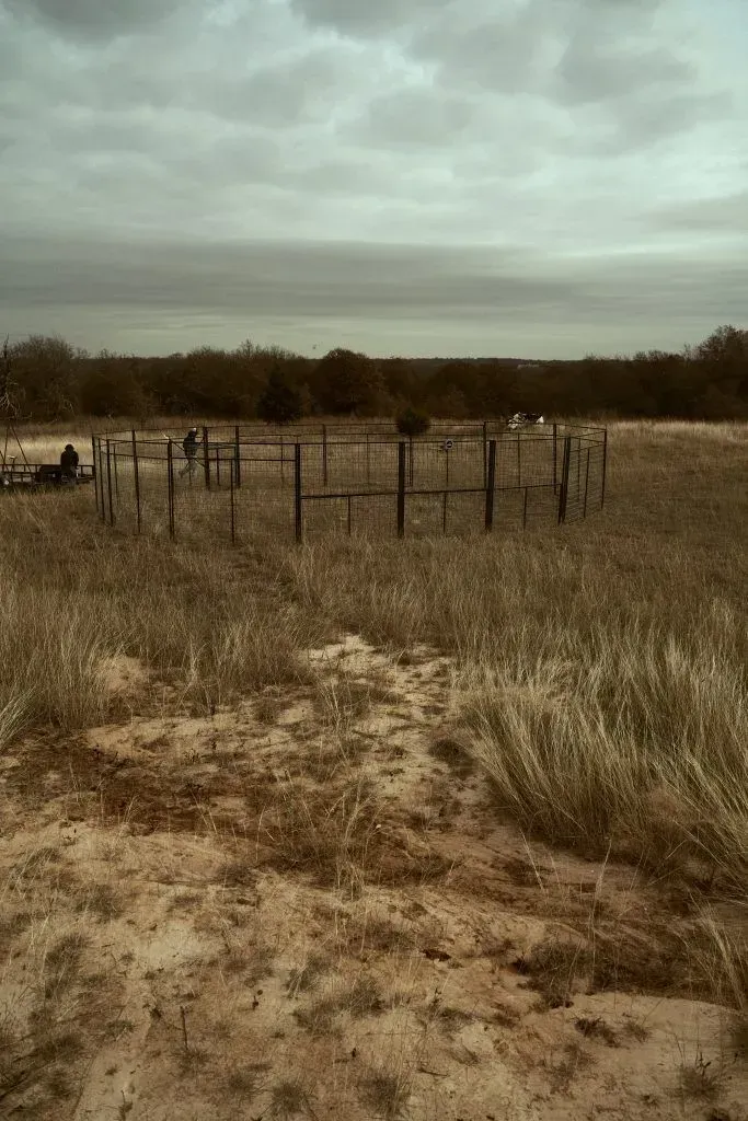 A brown field under a cloudy sky, with a circular metal structure in the center.