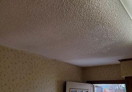 Textured ceiling with a large water stain above a room doorway.