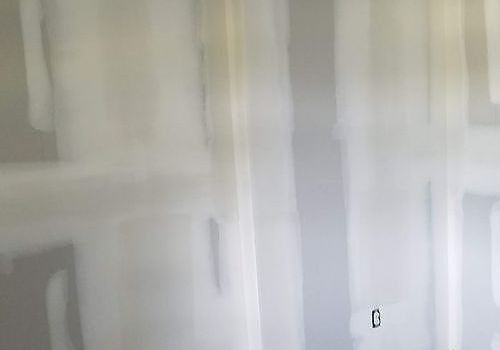 White paneled wall or cabinet doors with narrow vertical handles, softly lit indoors.