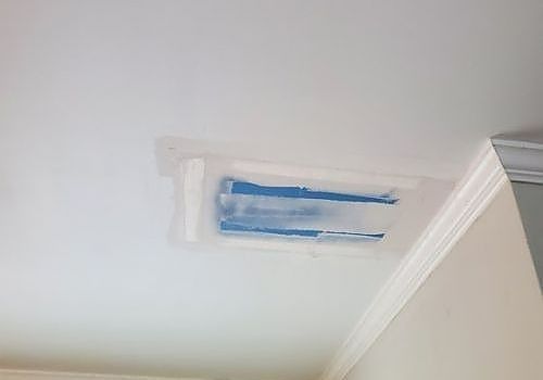 Painted ceiling patch with taped-off rectangular opening near crown molding