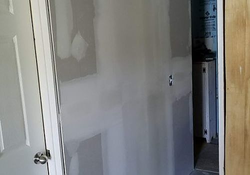 White hallway with a partially open door showing a kitchen beyond.