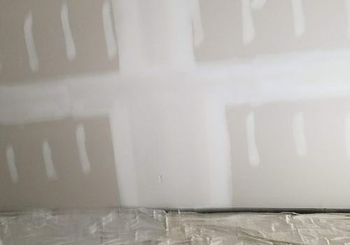 Unfinished drywall with taped seams and joint compound near the bottom edge