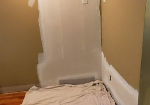 Partially painted wall corner with drop cloths on the floor in a room under renovation