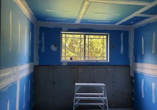 Blue room interior with a window, gray lower walls, and a small step ladder centered below the window