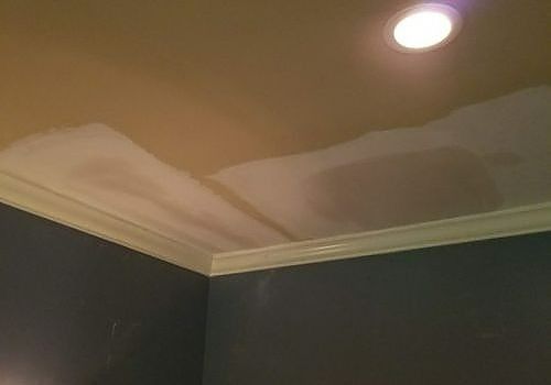 Ceiling corner with water-stained paint and a recessed light fixture