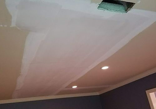 Ceiling with a large taped or plastered repair patch and recessed lights in a room