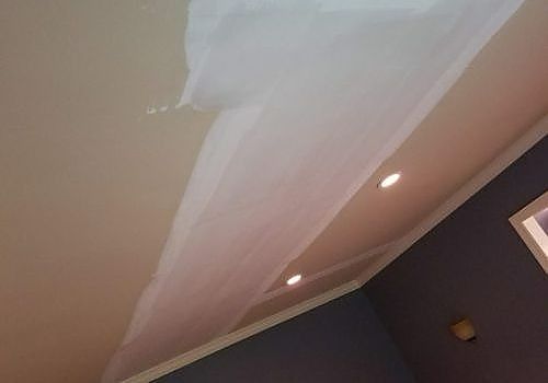 Ceiling corner with white draped fabric and recessed lights in a room