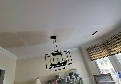 Ceiling light fixture in a room with a white ceiling, window blinds, and furniture below