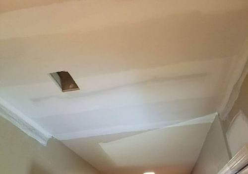 Ceiling with a rectangular opening and white crown molding in a hallway