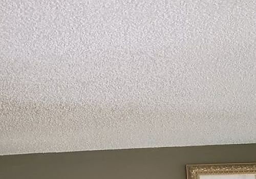 Textured white ceiling above a beige wall with the top of a framed picture visible