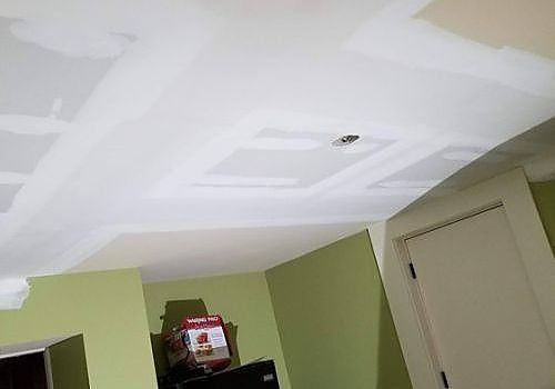 Tilted view of a room with a white ceiling, green walls, and a door, with a smoke detector near the center.