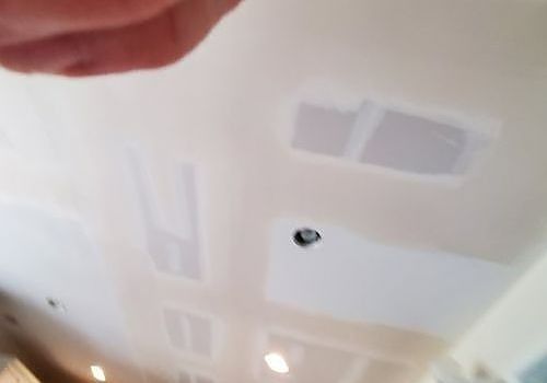 Ceiling with white patches around a small hole, with a finger visible at the top edge.