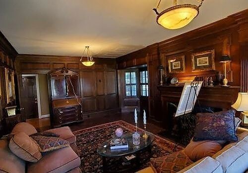 Wood-paneled living room with sofa, coffee table, fireplace, and antique furnishings