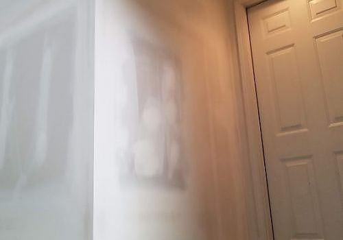 Blurred hallway corner with a white door and light-colored wall art.