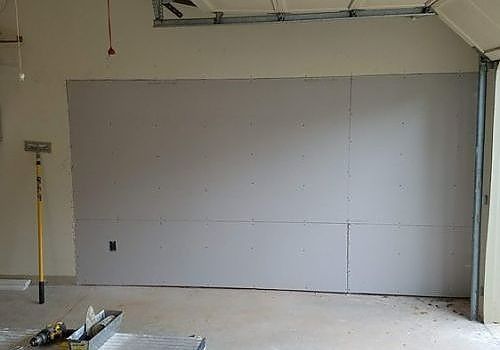 Unfinished interior wall with drywall panels in a bare room under renovation.