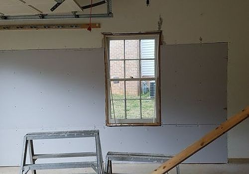Garage interior with unfinished walls, a small window, and stacked ladders under construction