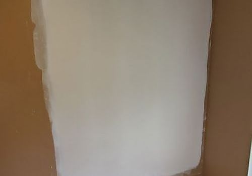 White painted patch on a tan wall with rough edges