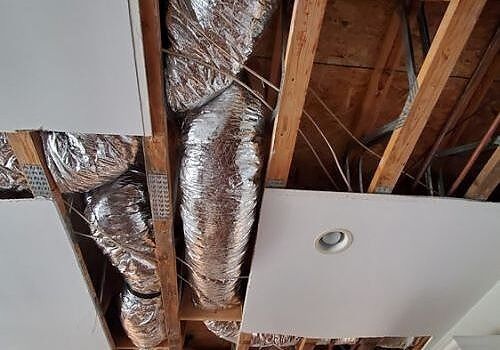 Ceiling under construction with exposed wooden beams, ductwork, and recessed light fixtures