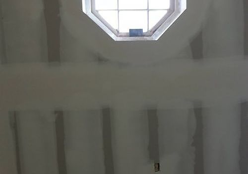Ceiling with octagonal skylight above unfinished gray walls and vertical paint streaks