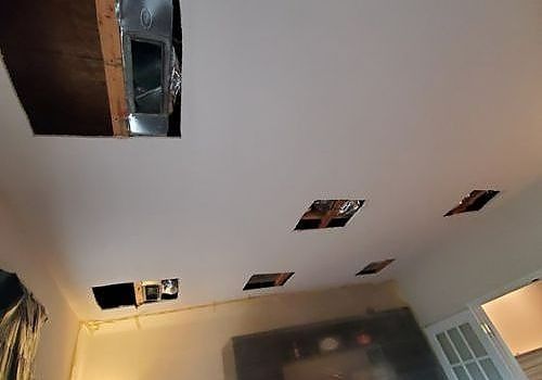 Ceiling with multiple rectangular holes, exposing dark attic space above a room.