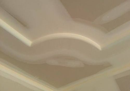 Close-up of a beige ceiling with decorative molding and curved recessed trim